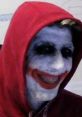 Smiling figure with painted white face and red joker smile, wearing a red hoodie, embodying Tense1983 2024 V2 character style.