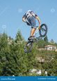 BMX rider performing an impressive jump against a clear blue sky, showcasing extreme sports skills and agility.