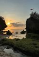 Sunset view at a serene beach with rocks and green moss, featuring a flag atop a natural formation. Ideal for nature lovers.