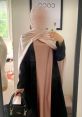 Stylish outfit featuring a beige and black abaya, accessorized with a chic handbag, reflecting modest fashion trends.