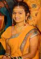 Young woman dressed in vibrant yellow saree adorned with jewelry and intricate henna designs, smiling radiantly at a festive celebration.