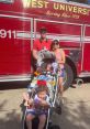 Family posing in front of a West University fire truck, celebrating a festive occasion with patriotic outfits and decorations.