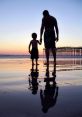 Father and son holding hands on a beach at sunset, reflecting a joyful family bond and summer memories.