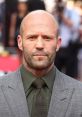 Jason Statham in a stylish gray suit and tie, exuding confidence at a red carpet event. Hollywood actor's striking presence.