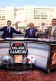 ESPN College GameDay hosts celebrate while showcasing football helmets, capturing the excitement of college sports.