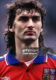 Kusarek CZE focused look in a red jersey with national emblem, showcasing determination during a football match.