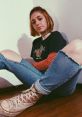 Casual style portrait of a young woman with short hair, wearing a graphic tee and ripped jeans, exuding laid-back vibes.