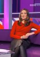 Laura M2009 in a stylish red top and leather skirt, seated on a purple couch, discussing trending topics on BBC Scotland.