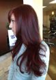 Dark red hair styled in long, flowing layers, showcased in a salon setting with contemporary decor.