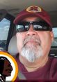 Alfredo Loya wearing sunglasses and a maroon cap with a logo, capturing a casual moment inside a vehicle.