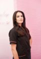 Martina Camarasa Carbonell posing confidently in a stylish black uniform with pink accents, set against a vibrant pink backdrop.