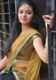 Young woman in elegant traditional attire, showcasing grace and style with a golden saree and intricate accessories.