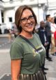 Smiling woman in a green shirt with "Crown" design, showcasing style and confidence in a lively urban setting.