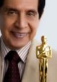 Fernando Landín smiles proudly holding an Oscar statue, showcasing his achievements in film and entertainment.