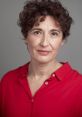 Professional portrait of a woman with curly hair wearing a red shirt, showcasing confidence and expertise. MiriamPM style.