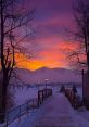 Serene winter sunset over a snow-covered path, with glowing streetlights and mountains in the background.