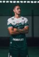 Ageu Sousa in athletic pose, showcasing team jersey with green and white design, confident expression and crossed arms.