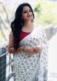 Akhila Chavan radiates elegance in a white saree with intricate patterns, enjoying a sunny day outdoors.