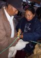 Couple handling a bird at a market, highlighting traditional practices in the Familia Amagua community.