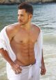 Stylish male model at the beach, showcasing a fit physique and an effortless summer look with flowing white attire.