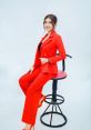 Vo Hanh showcasing a stylish red suit, exuding confidence and elegance while seated on a stool. Perfect for fashion inspiration.