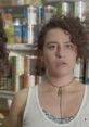 Ilana Glazer looks astonished while shopping in a grocery store, surrounded by colorful canned goods.