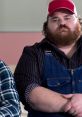 Character from "Letterkenny" displaying a serious expression, wearing overalls and a red cap, embodying rural Canadian humor.