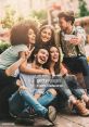 Friends laughing together outdoors, capturing joyful moments with a smartphone, showcasing happiness and fun.