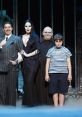 The Addams Family cast in quirky costumes, featuring Morticia, Gomez, Uncle Fester, and Wednesday Addams.