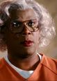 Madea character with silver hair and glasses, wearing an orange outfit, showcasing a dramatic and expressive look.