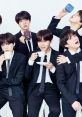 BTS members in stylish suits enjoying drinks, showcasing their charismatic personalities and brotherly bond at a photoshoot.