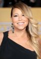 Mariah Carey smiles brightly, showcasing her glamorous style with elegant earrings and soft waves at a star-studded event.