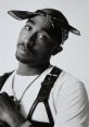 2Pac posing in a black and white photo, wearing a bandana and leather harness, exuding his iconic street artist style.