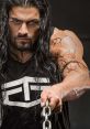 Roman Reigns showcases strength and intensity while gripping a chain, exuding power in a dramatic pose.