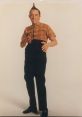 Ed Grimly showcases a quirky pose with a distinct hairstyle, dressed in a plaid shirt and high-waisted pants.