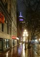 Rain-soaked street at night featuring a pizza shop and a lit tower, ideal for exploring Warren Woodward's YouTube adventures.