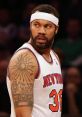 Rasheed Wallace in New York Knicks jersey, showcasing his striking tattoo and intense game focus on the court.