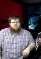 Angry Joe Show discussion featuring a man with glasses and a beard, expressing a serious demeanor in a studio setting.