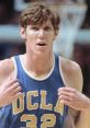 Bill Walton in a UCLA jersey, showcasing his iconic number 32 during an intense basketball game moment.