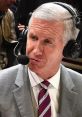 Mike Breen provides live commentary at a basketball game, wearing a suit and headset, focused on the action.