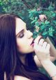 Young woman gently interacting with vibrant flowers, showcasing nature's beauty and delicate moments amidst greenery.