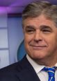 Sean Hannity smiling on set, wearing a suit and tie, with a backdrop reflecting a professional news environment.