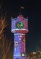 Colorful light projections on Helder water tower at night, featuring an eye and intricate designs, capturing vibrant art.