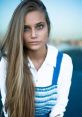 Portrait of a Russian girl with striking blue eyes and long hair, wearing a blue and white outfit, exuding elegance and confidence.