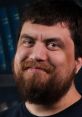 Ryan from the UK with a cheerful expression, showcasing a full beard against a blurred background of books.