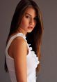 Young woman with long hair posing confidently, showcasing Hungarian style and elegance in a chic white top.