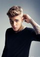 Justin Bieber poses confidently in a stylish black shirt, showcasing his signature look and tattoo, exuding charisma.